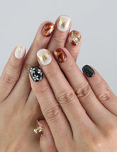 Model wearing Floral Glow Naillover press on nails, showing floral detailing and pearl accents on mixed neutral tones.